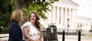 Kristen Waggoner and Lorie Smith sit on a bench outside of the Supreme Court building in Washington, D.C.