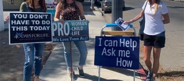 Sidewalk counselors with Right to Life of Central California stand with signs on a sidewalk