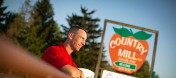 Steve Tennes of Country Mill Farms stands in front of his family farm's sign