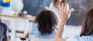 A student is seen raising her hand in class