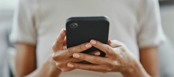 A woman is seen looking a phone she's holding in her hands