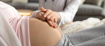 Pregnant woman with a doctor placing their hands on the mother's womb