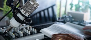 A microphone and Bible sit on a broadcaster's desk