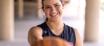 Amelia Ford smiles as she holds a basketball out toward the camera