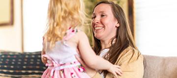 Katy Wuoti smiles and holds her daughter