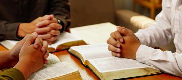 People sit together praying and reading the Bible