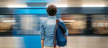 A man stands at a train station as a train goes by