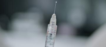 A syringe is seen against a blurry gray background