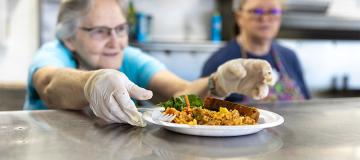 Workers in the kitchen serve a plate of food at Yakima Union Gospel Mission