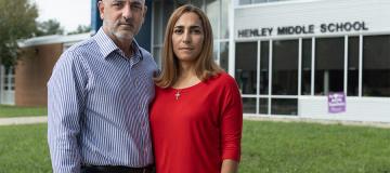 Carlos and Tatiana Ibanez stand in front of Henley Middle School with serious expressions on their faces