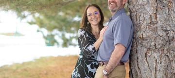 Joe and Serena Wailes smile as they lean against a tree