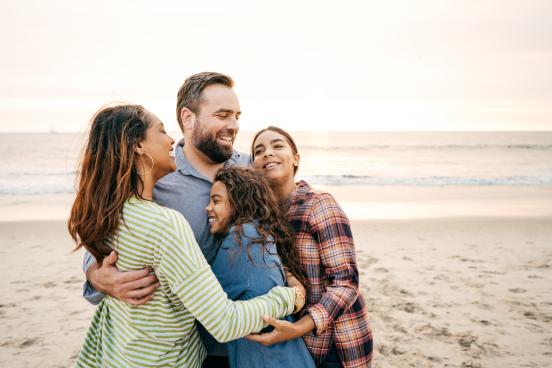 Parents hugging children on the beach