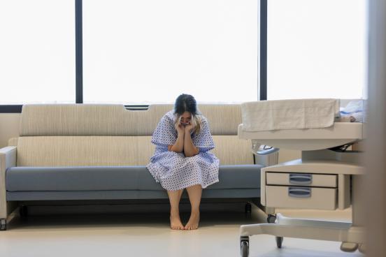 Woman sitting on a couch in a hospital gown