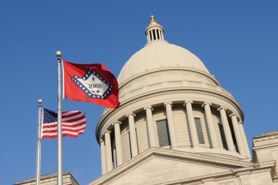 Arkansas capitol building with state and U.S. flags