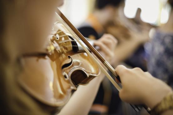 Girl playing violin in an orchestra