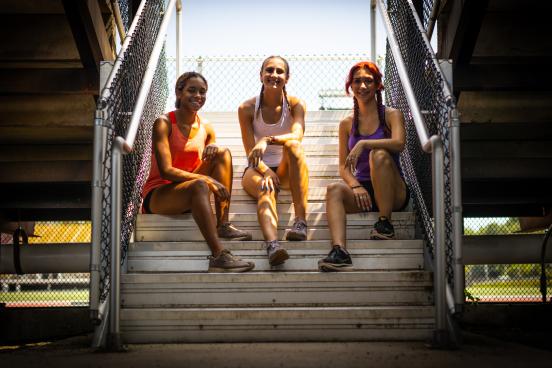 Selina Soule, Chelsea Michell, and Alanna Smith sitting on bleacher stairs