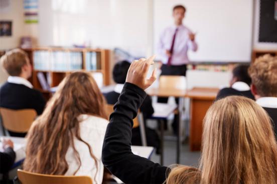 High school classroom with teen girl raising hand