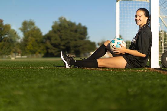 West Virginia soccer player Lainey Armistead leans against a soccer goal