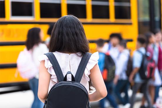 Girl with a backpack getting on the school bus