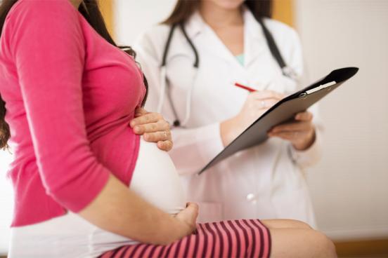 Pregnant woman with a female doctor with a clipboard