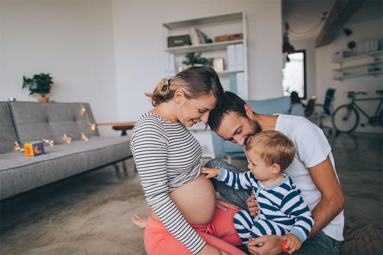 A toddler with his parents touches his mother's pregnant belly