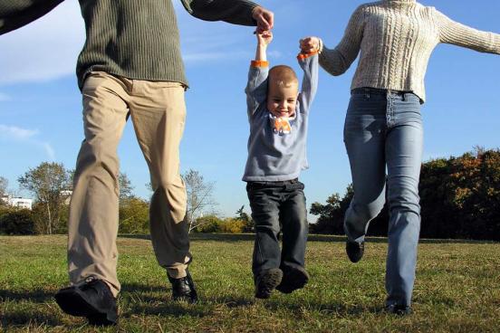 A young boy holding his parents' hands