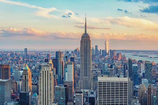 Sunlight illuminates the clouds behind the New York City skyline