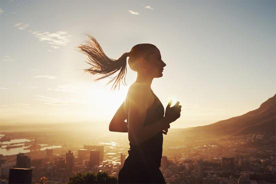 Female athlete running overlooking city into the sun