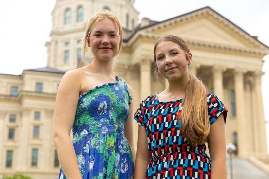 Sisters Aubrey and Avalon Simpson stand in front of the Kansas State Capitol