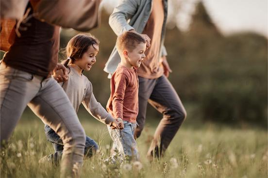 Kids holding hands with their parents in a field