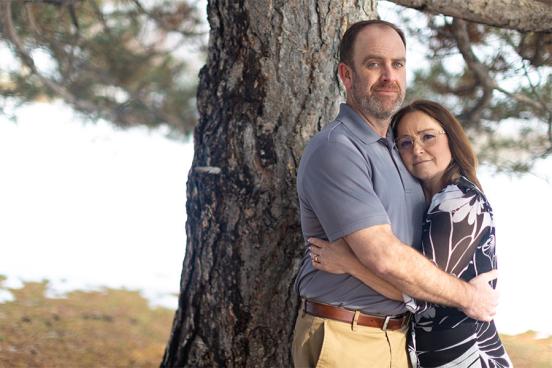 Joe and Serena Wailes hugging and standing by a tree