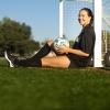 West Virginia soccer player Lainey Armistead leans against a soccer goal