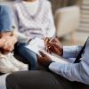 A counselor takes notes as he talks with a child and parent