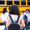 Girl with a backpack getting on the school bus