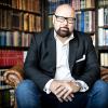 Dr. Andrew Fox sits in a leather chair in his home library