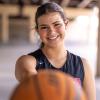 Amelia Ford smiles as she holds a basketball out toward the camera