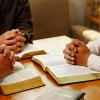 People sit together praying and reading the Bible