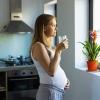 A pregnant woman is pictured in her kitchen looking out the window