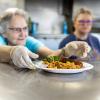 Workers in the kitchen serve a plate of food at Yakima Union Gospel Mission